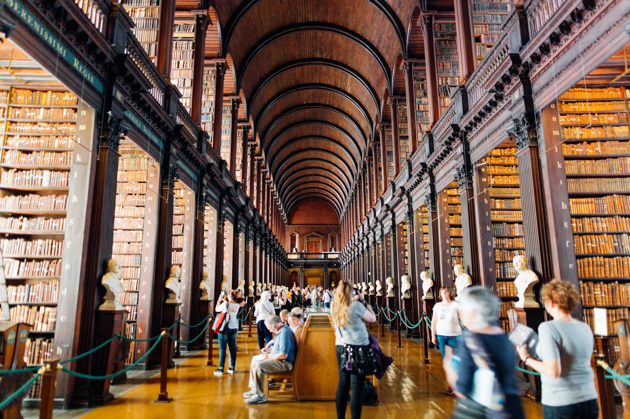 Crafting Captivating Headlines: Your awesome post title goes here Visitors explore a grand library hallway with towering bookshelves in an iconic university.