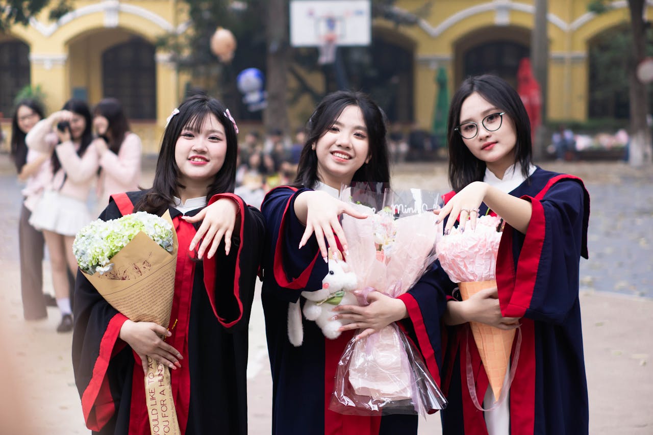 The Art of Drawing Readers In: Your attractive post title goes here Three young women celebrate graduation outdoors with bouquets and joyful smiles.